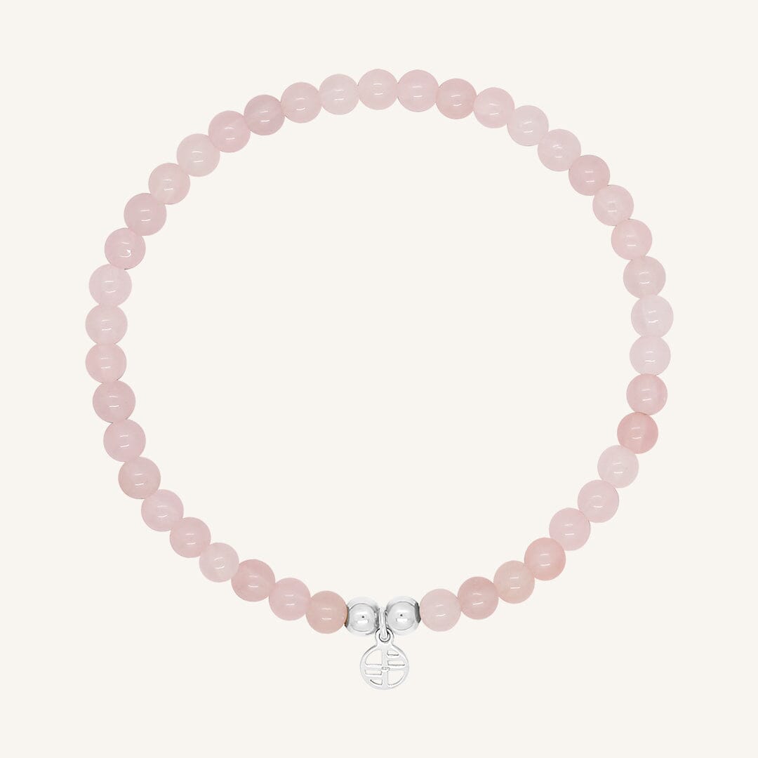 A rose quartz beaded bracelet with a silver charm, displayed against a white background.