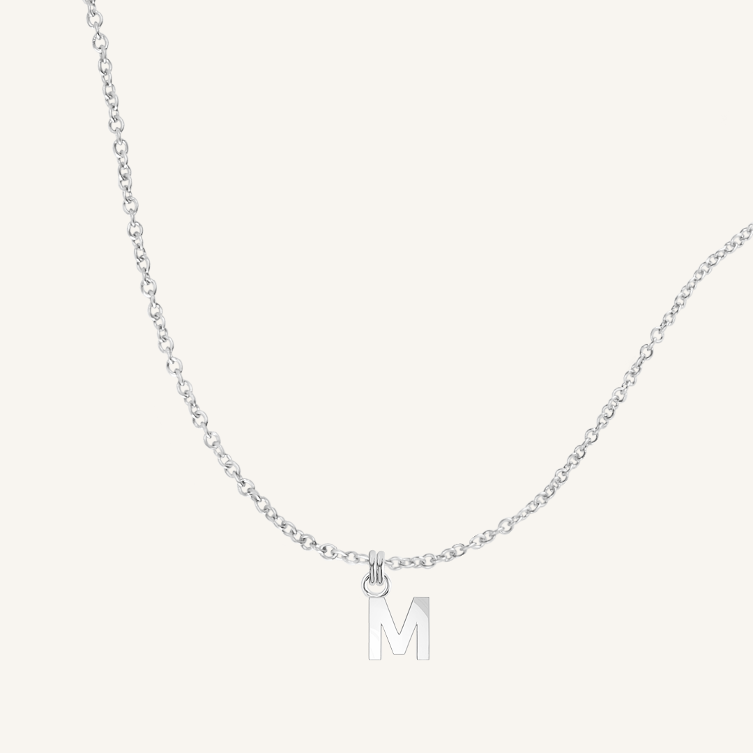 Silver necklace with a 'M' pendant on a light gray background