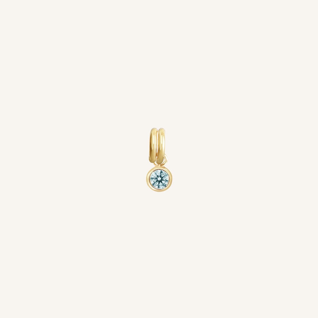 Round gold charm with bezel-set aquamarine cubic zirconia representing the March birthstone.