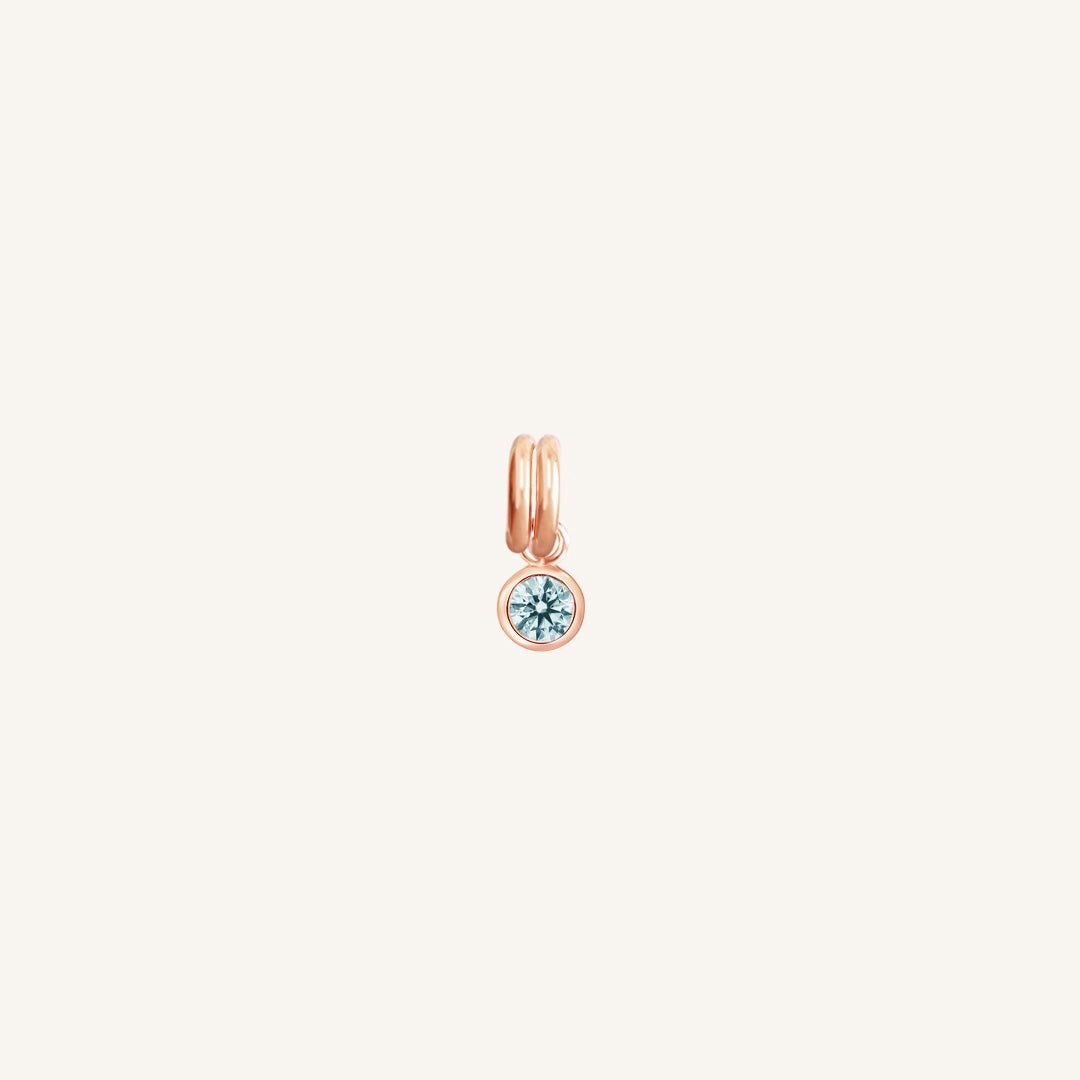 Round rose gold charm with bezel-set aquamarine cubic zirconia representing the March birthstone.