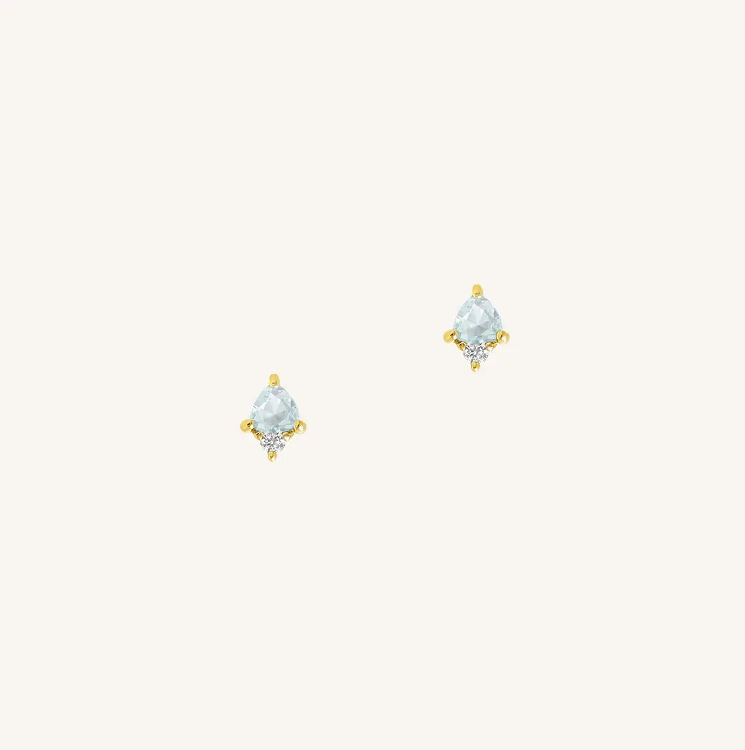 A gold pair of stud earrings featuring a blue cubic zirconia, representing March.