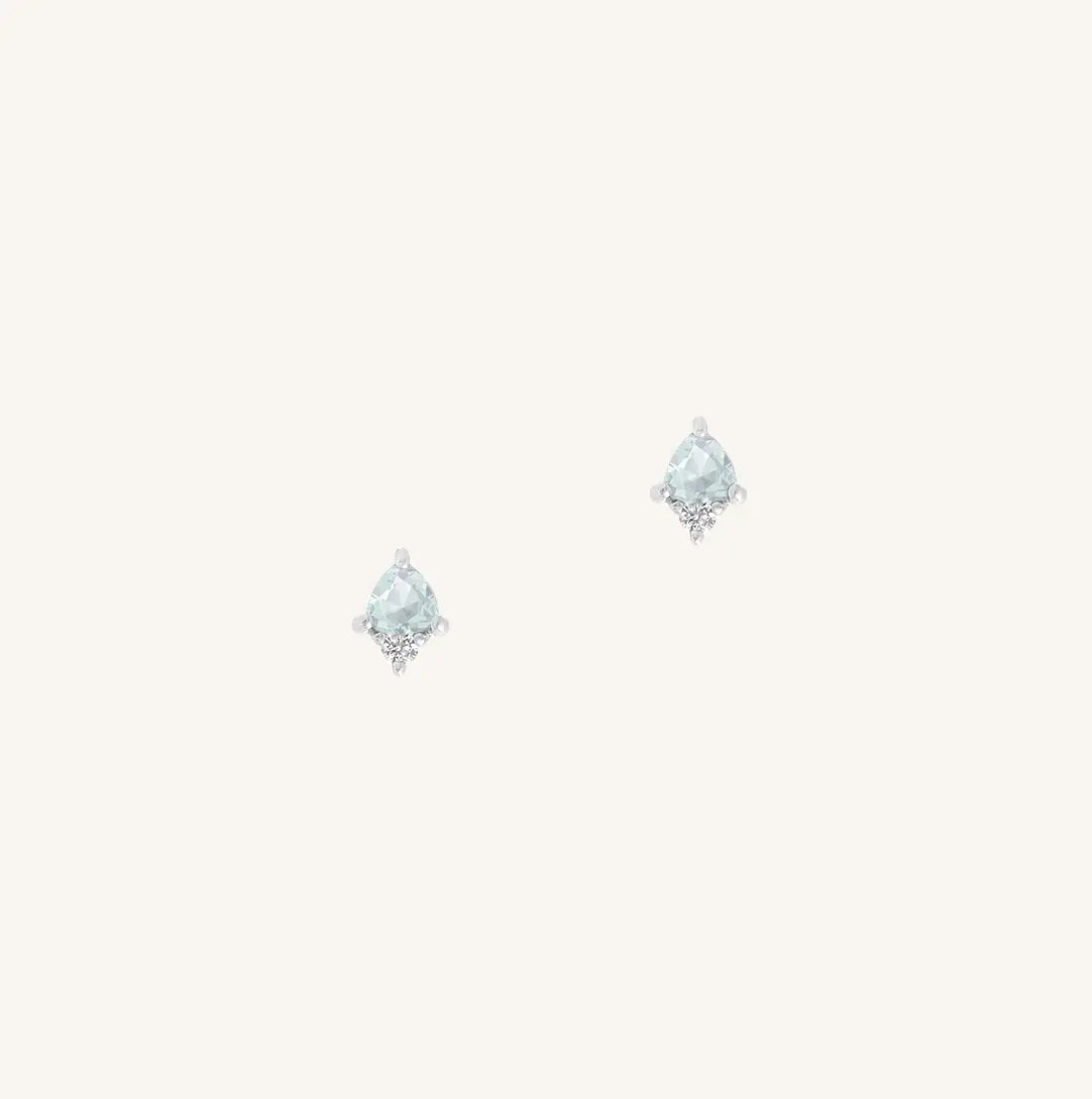 A silver pair of stud earrings featuring a blue cubic zirconia, representing March.
