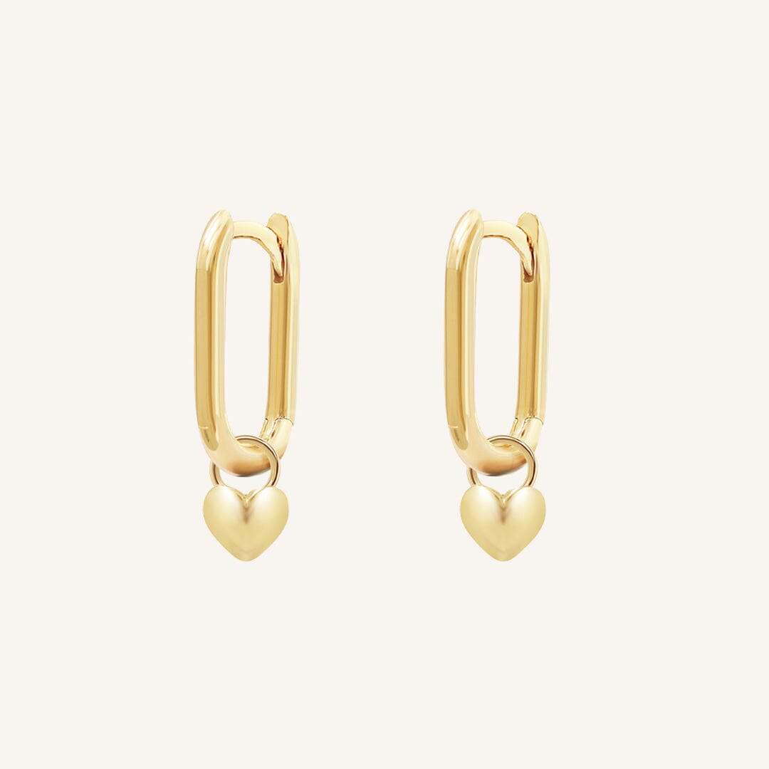 A pair of gold-tone hoop earrings with heart charms attached to them, displayed against a white background.
