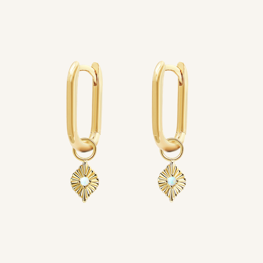 A pair of gold hoops with diamond shaped hoop charms featuring a faux opal, worn by model