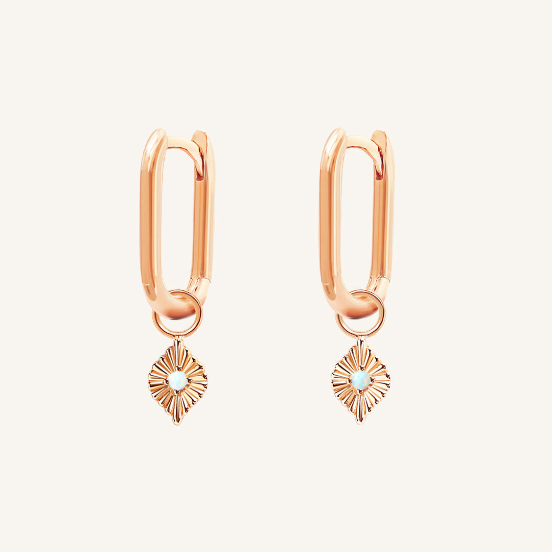 A pair of rose hoops with diamond shaped hoop charms featuring a faux opal, worn by model