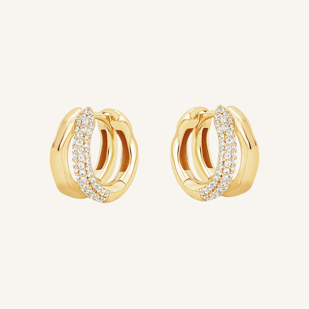 A pair of gold-coloured hoop earrings with a huggie design, featuring a layered look and pave white stones on one side.