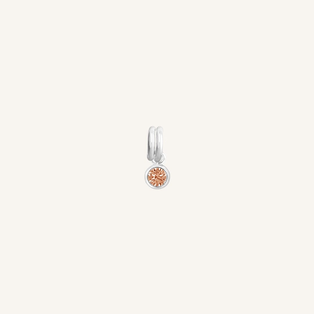 A round silver birthstone charm with a citrine cubic zirconia, symbolising the November birth month.
