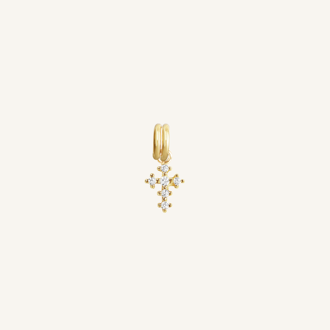 A petite gold cross charm with cubic zirconia on white background