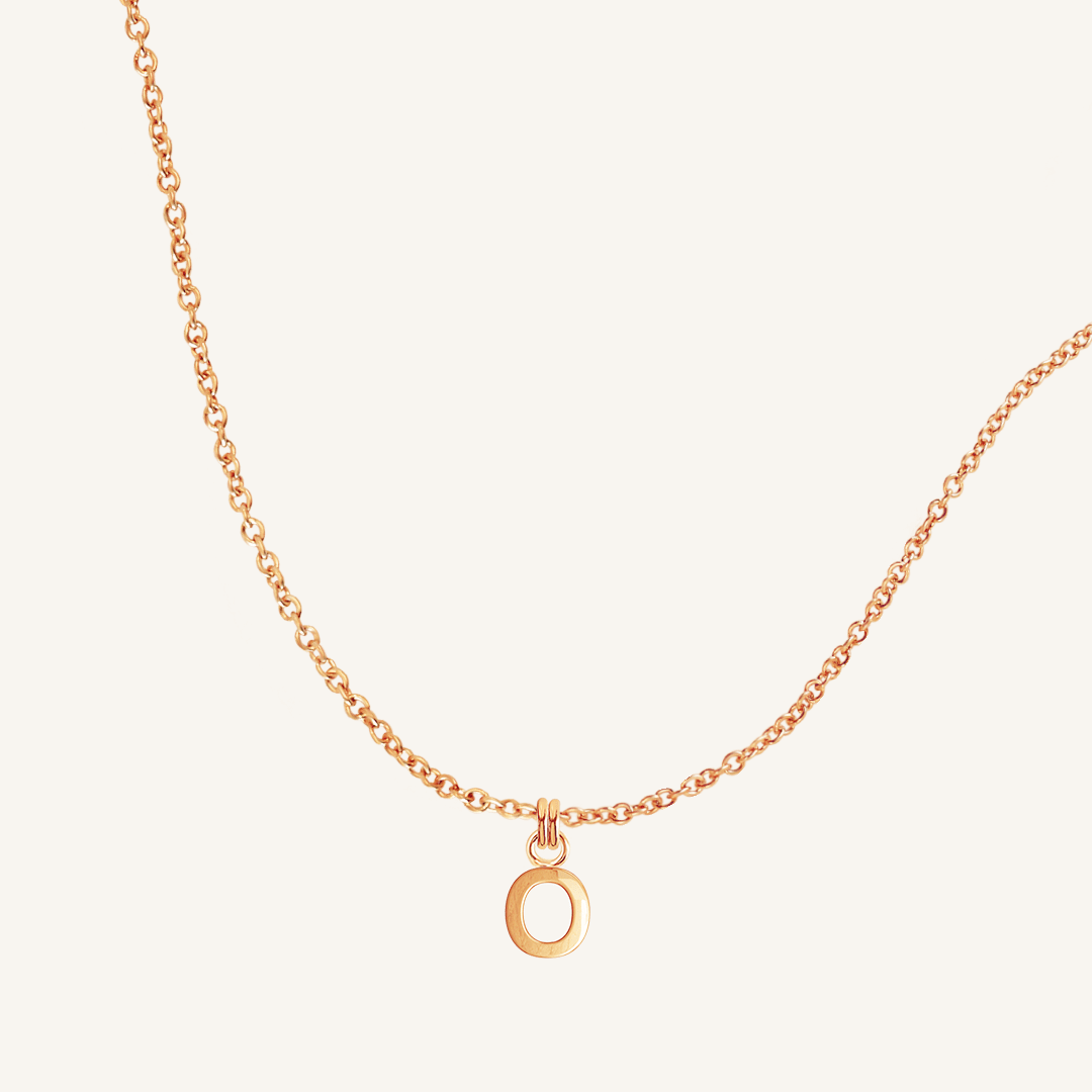 Rose gold necklace with an O round pendant on a light beige background
