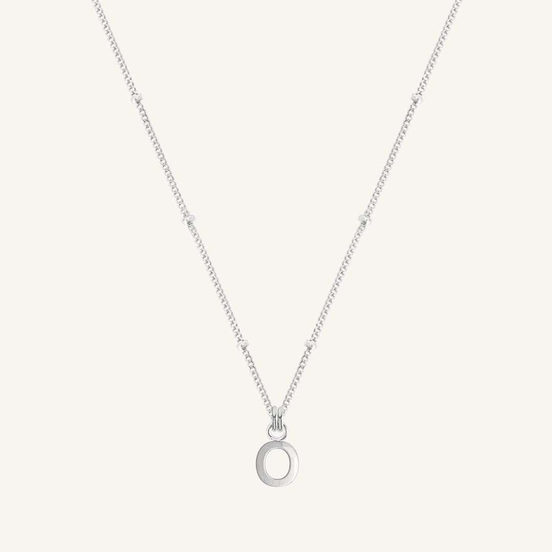 Silver necklace with an 'O' pendant on a light gray background