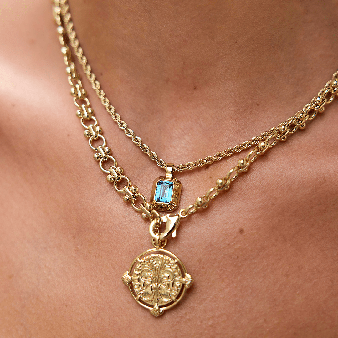 Gold charm with Blue emerald cut cubic zirconia bezel set Inspired by the halls of Versailles on neck