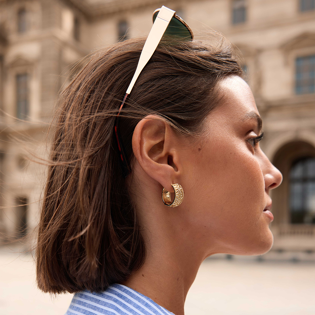 intricately designed statement gold hoops in the ear