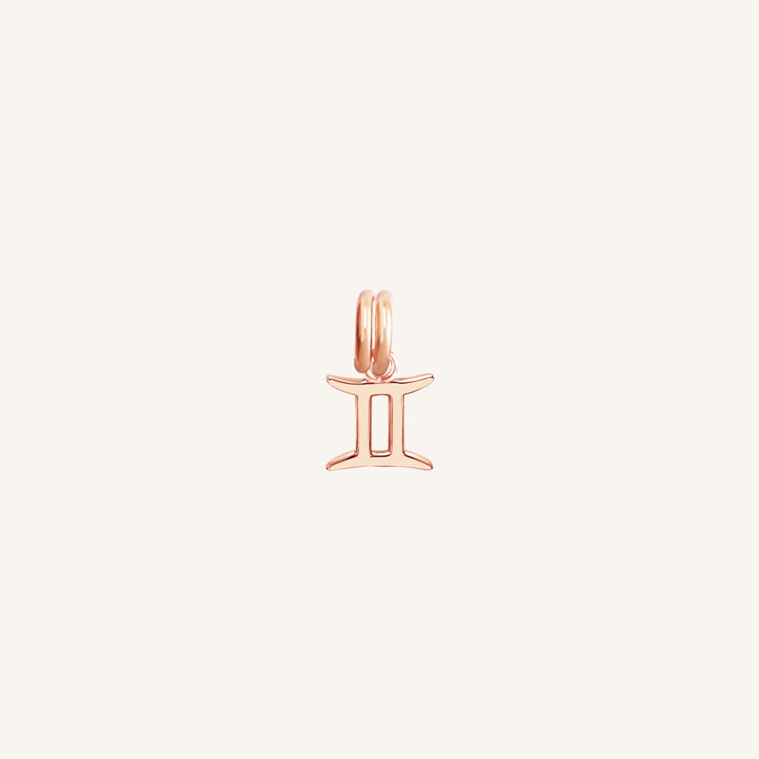 A rose gold charm representing the Gemini zodiac sign.