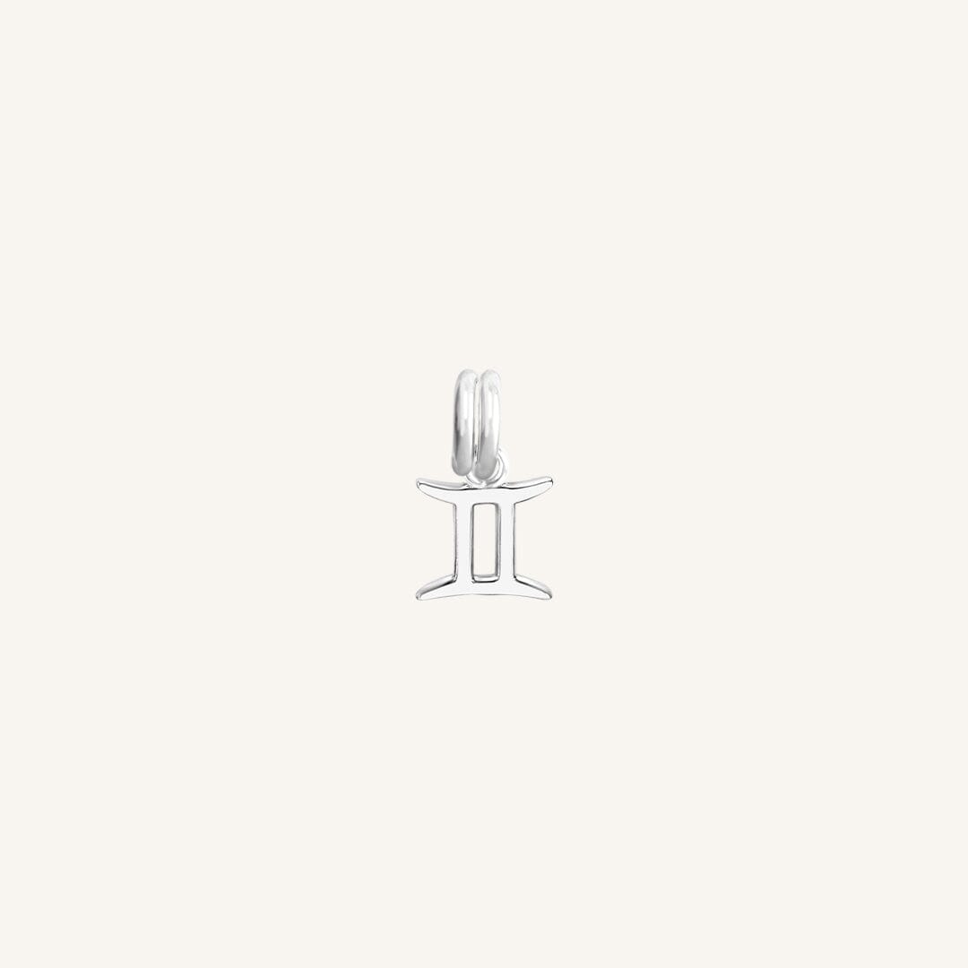 A silver charm representing the Gemini zodiac sign.