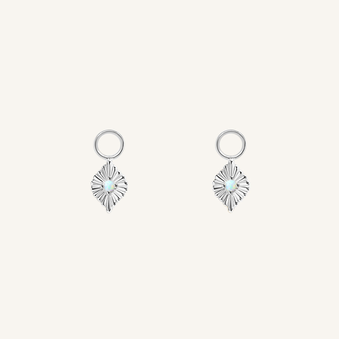 A pair of silver diamond shaped hoop charms featuring a faux opal