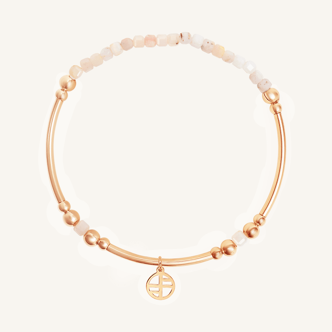 Rose gold bracelet with white beads on a light beige background