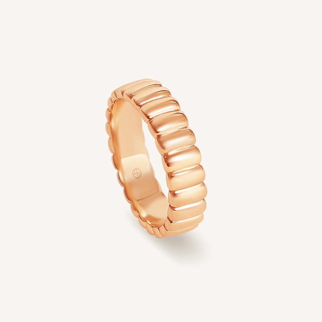 Rose gold ring with a ribbed design on a light gray background