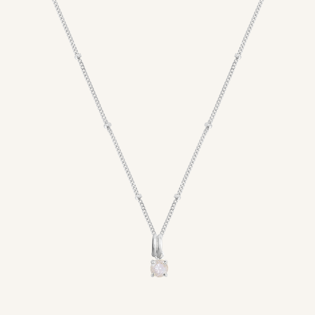 A silver charm necklace with a small moonstone pendant, isolated on a white background.