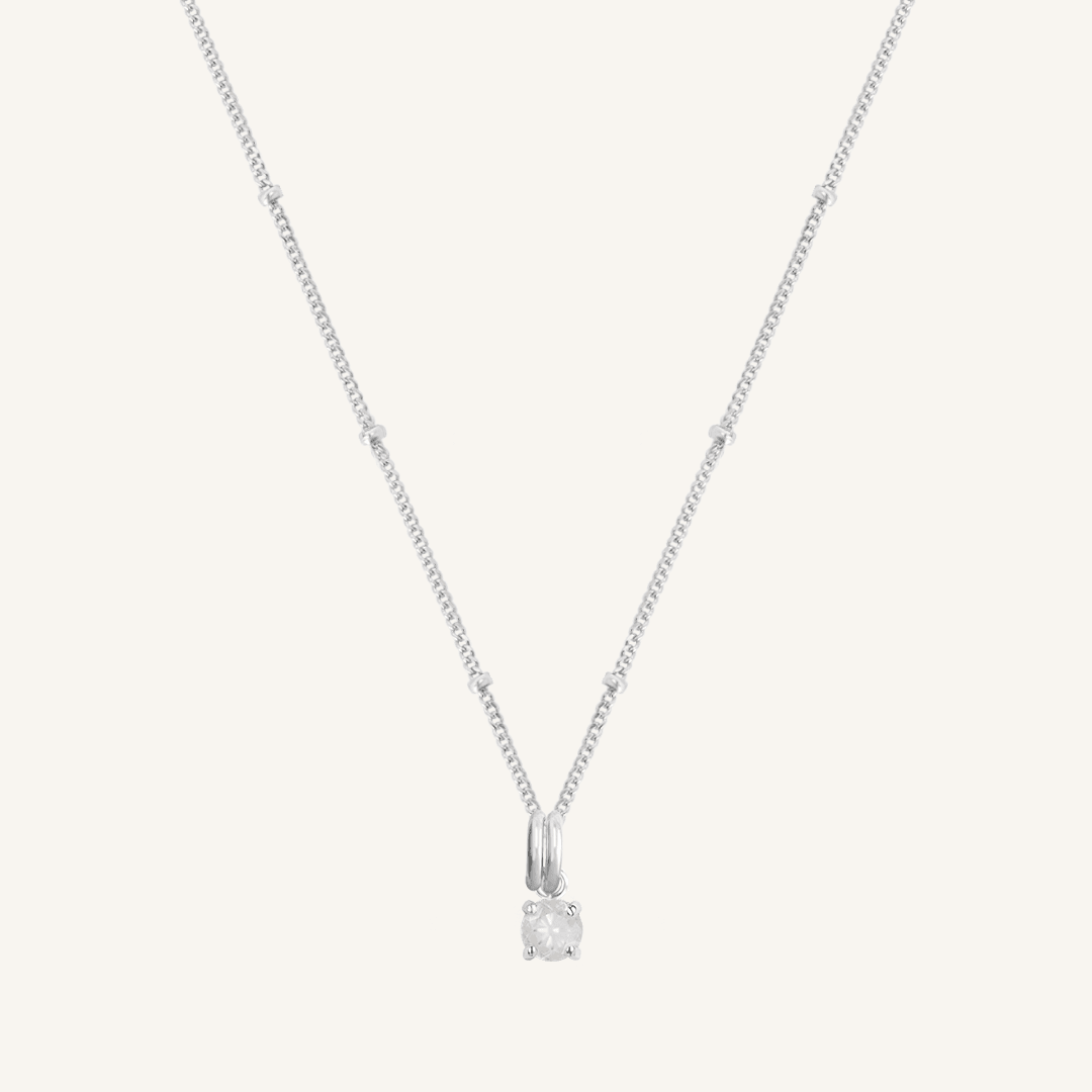 A silver charm necklace with a small moonstone pendant, isolated on a white background.