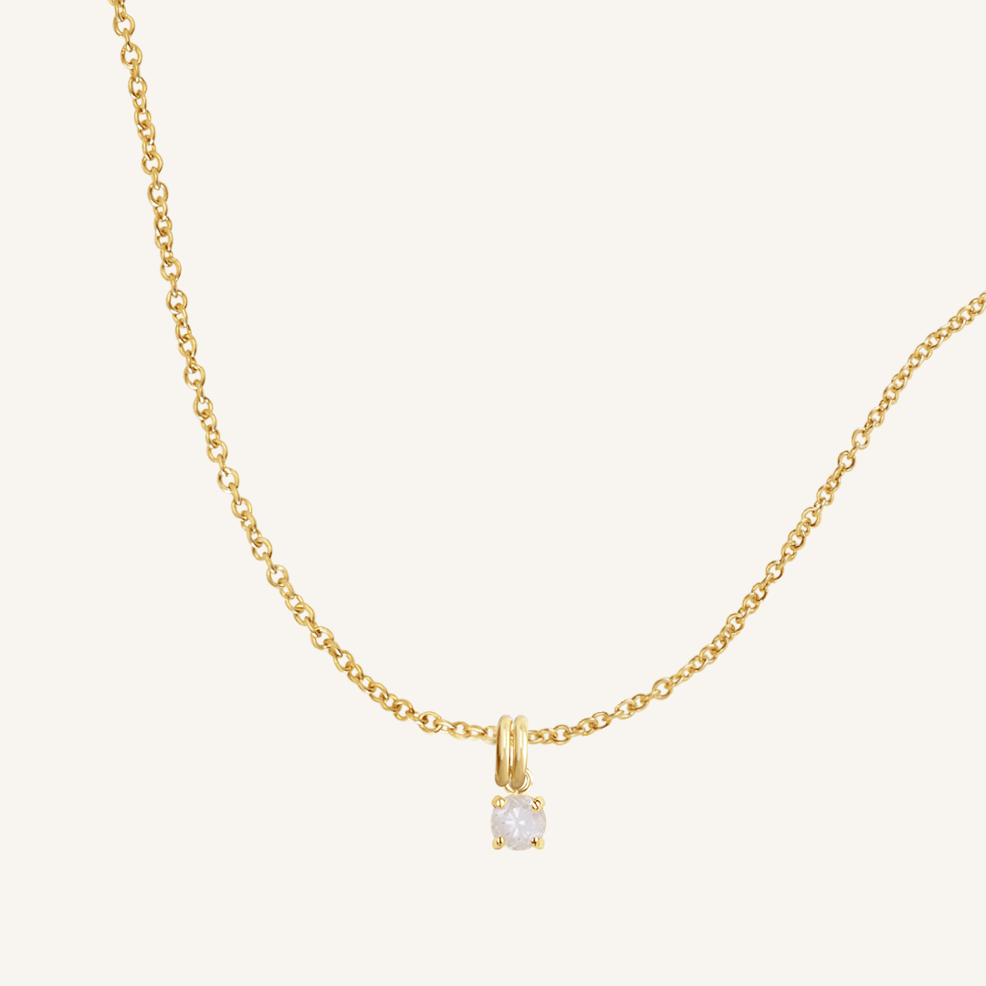 A gold-tone charm necklace with a small moonstone pendant, isolated on a white background.