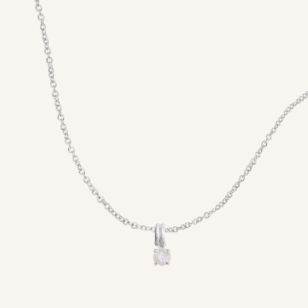 A silver charm necklace with a small moonstone pendant, isolated on a white background.
