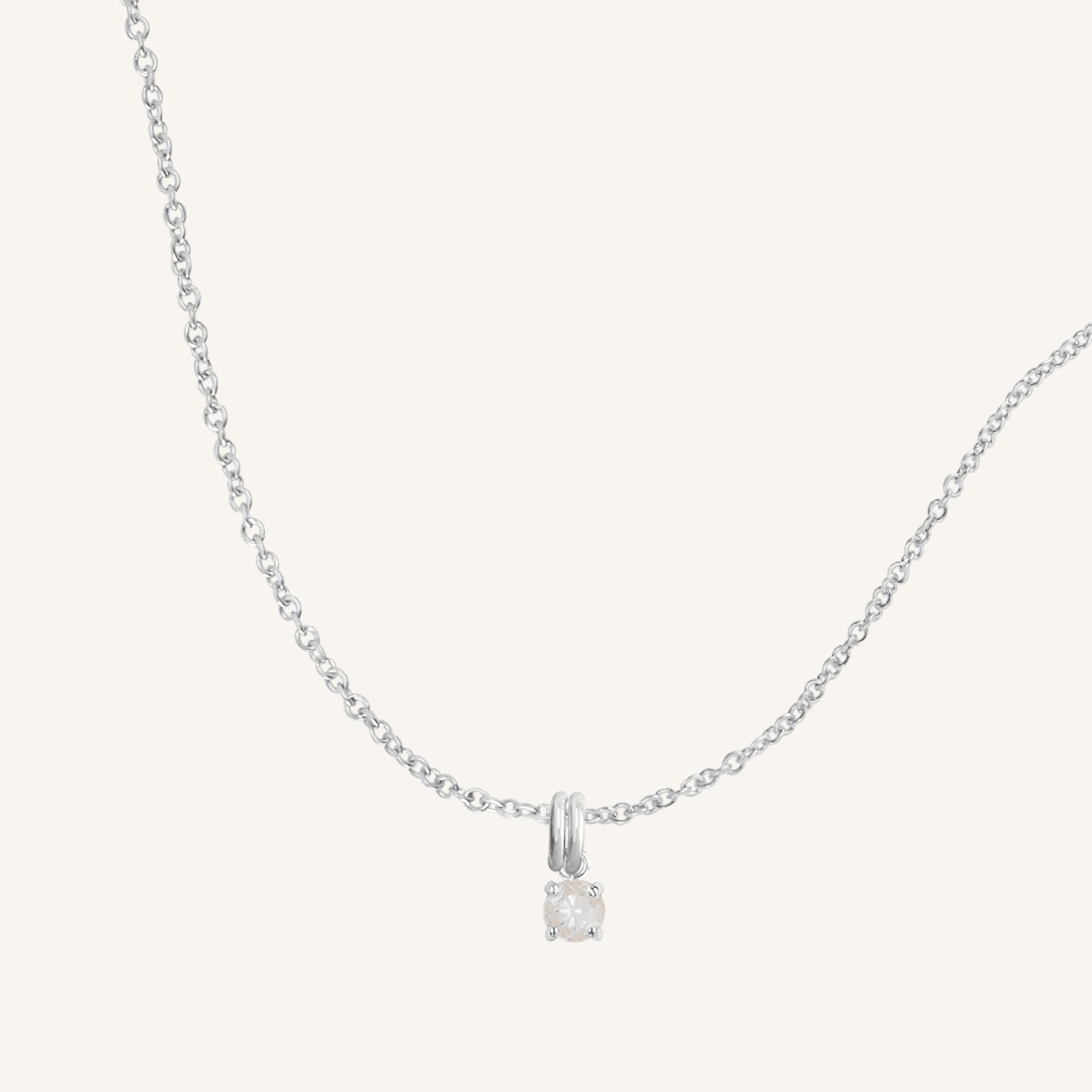 A silver charm necklace with a small moonstone pendant, isolated on a white background.
