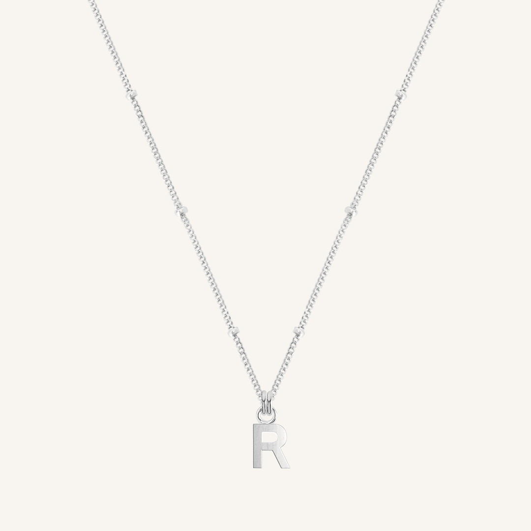 Silver necklace with 'R' pendant on a white background
