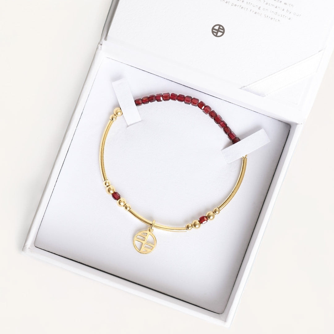 Gold bracelet with red beads in a white box
