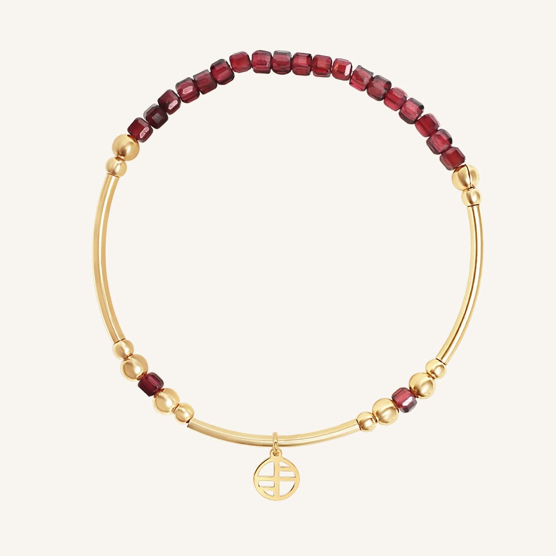 Gold bracelet with red beads on a white background