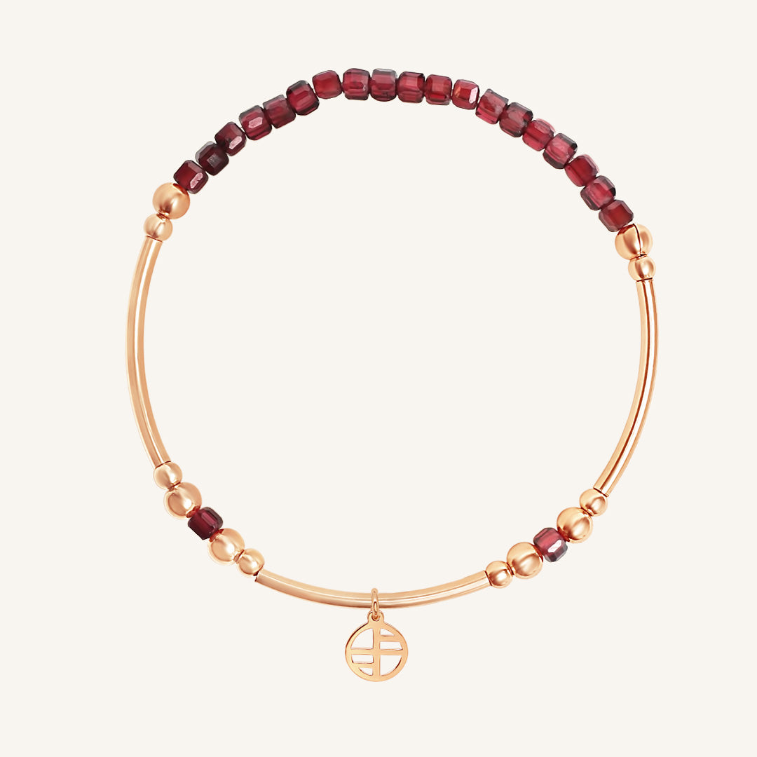 Bracelet with red beads and gold accents on a white background