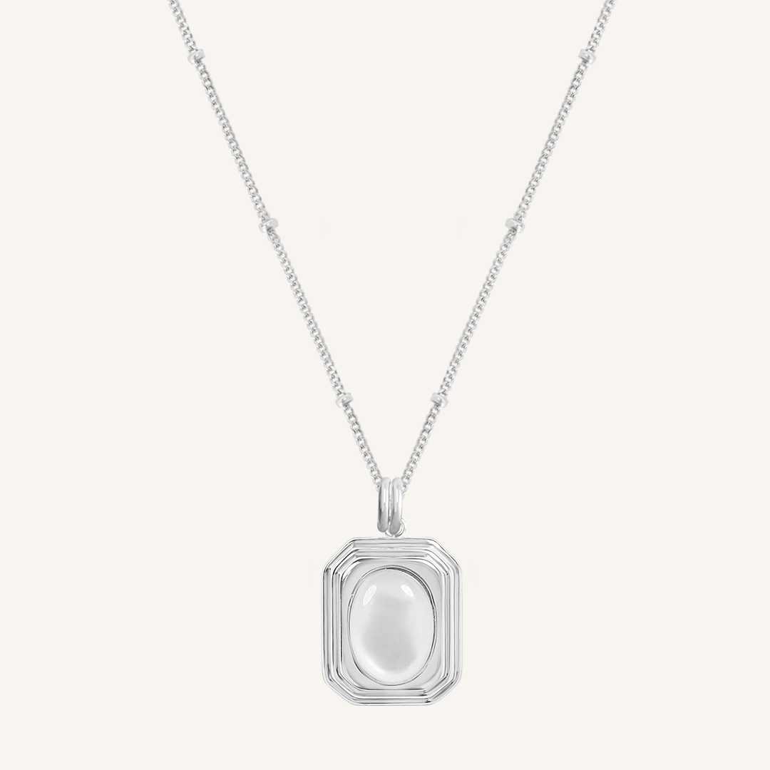 A silver-colored necklace with a square-shaped pendant featuring a mother-of-pearl stone.