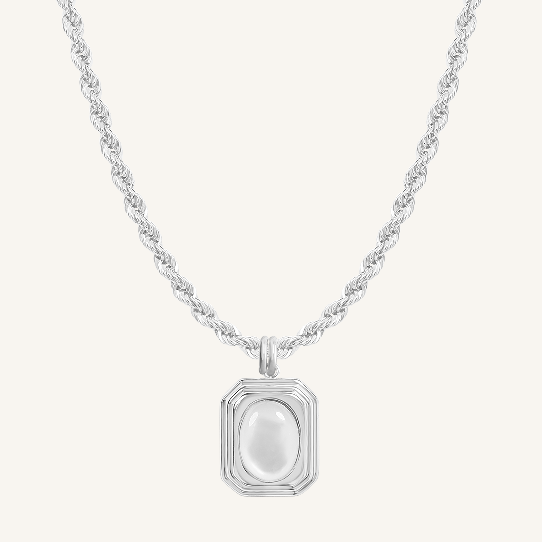 A gold-colored necklace with a square-shaped pendant featuring a mother-of-pearl stone.