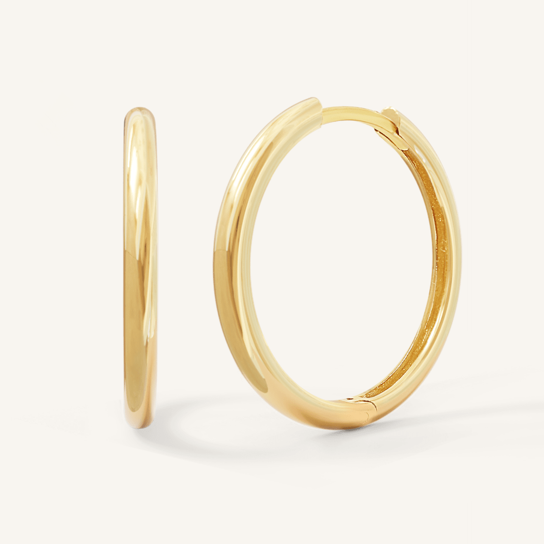 A pair of gold-tone hoop earrings on a white background