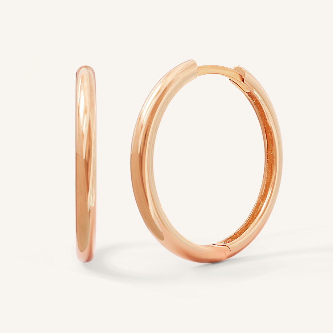 A pair of rose-tone hoop earrings on a white background