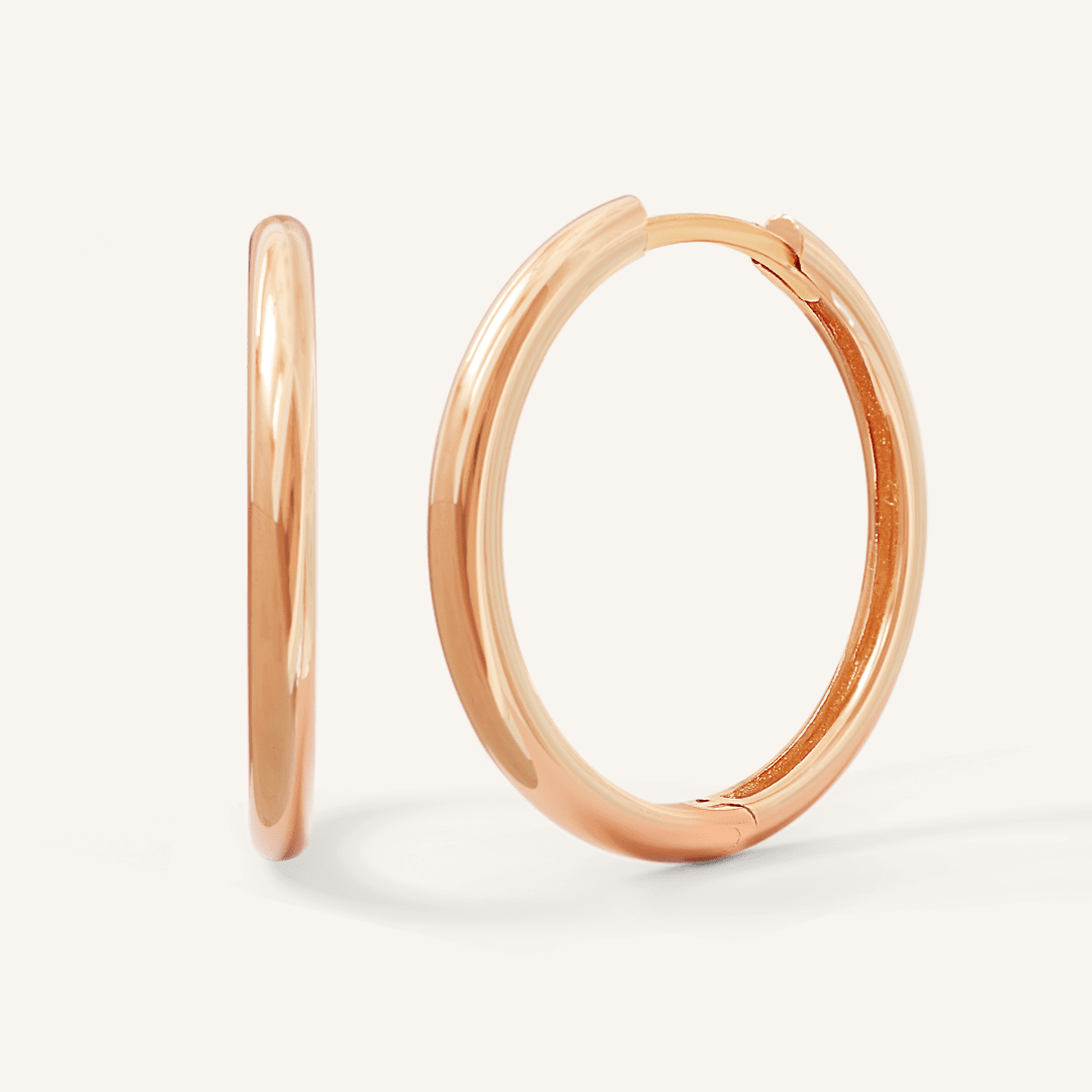 A pair of rose-tone hoop earrings on a white background