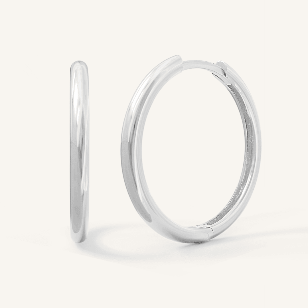 A pair of silver-tone hoop earrings on a white background