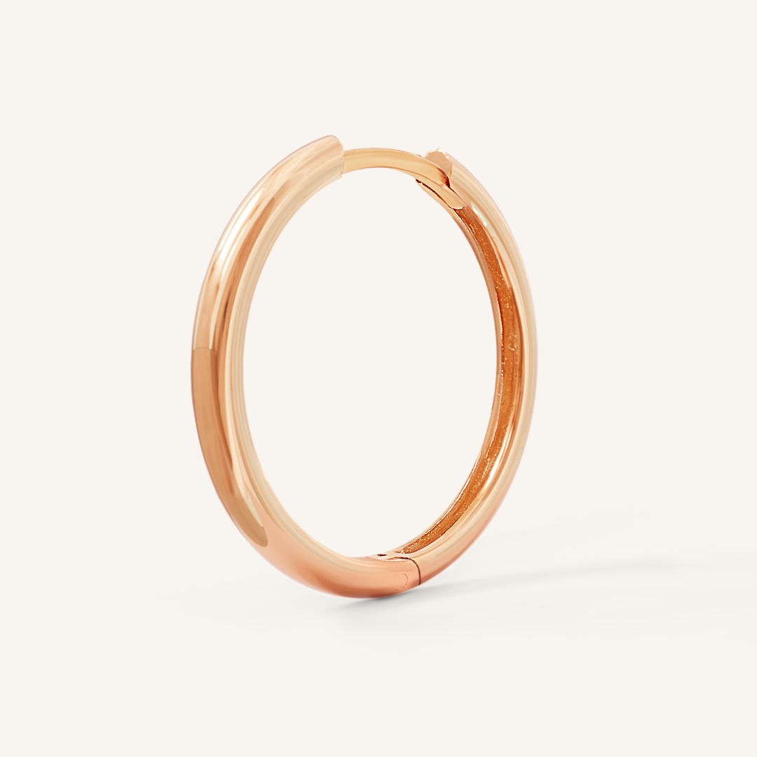 A rose-tone hoop earring on a white background