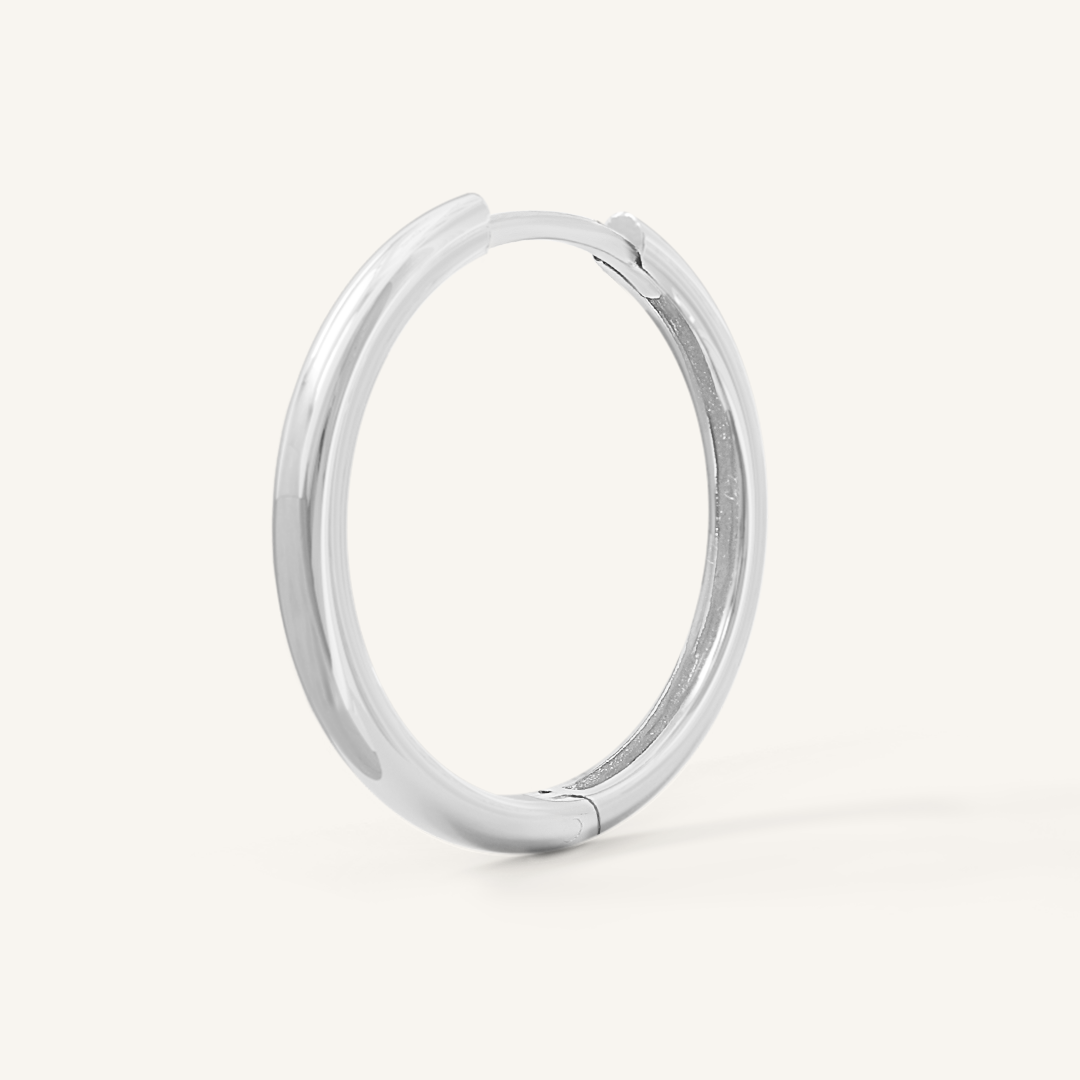 A silver-tone hoop earring on a white background