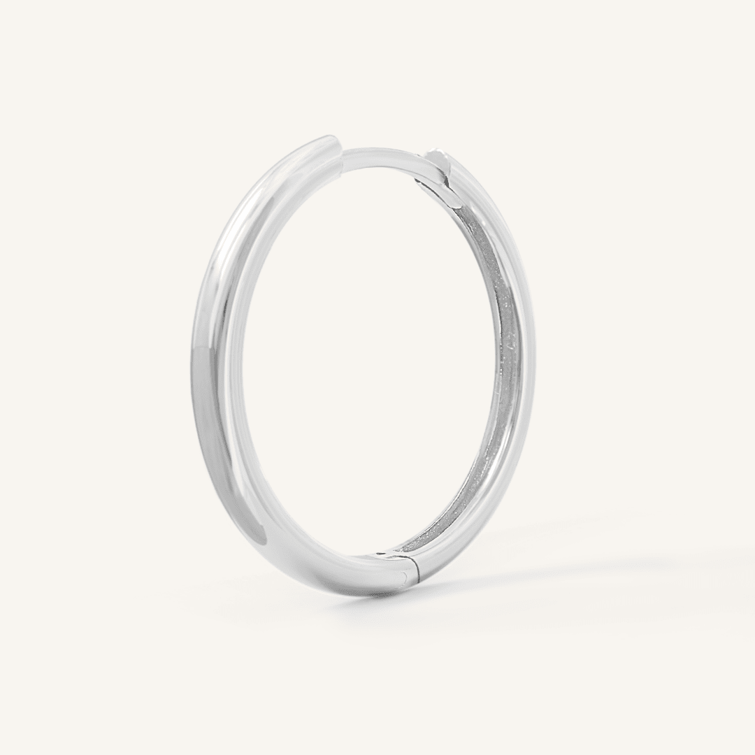 A silver-tone hoop earring on a white background