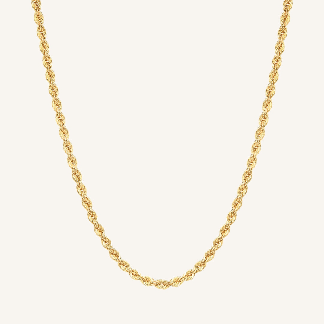 A gold rope chain necklace on a plain background.