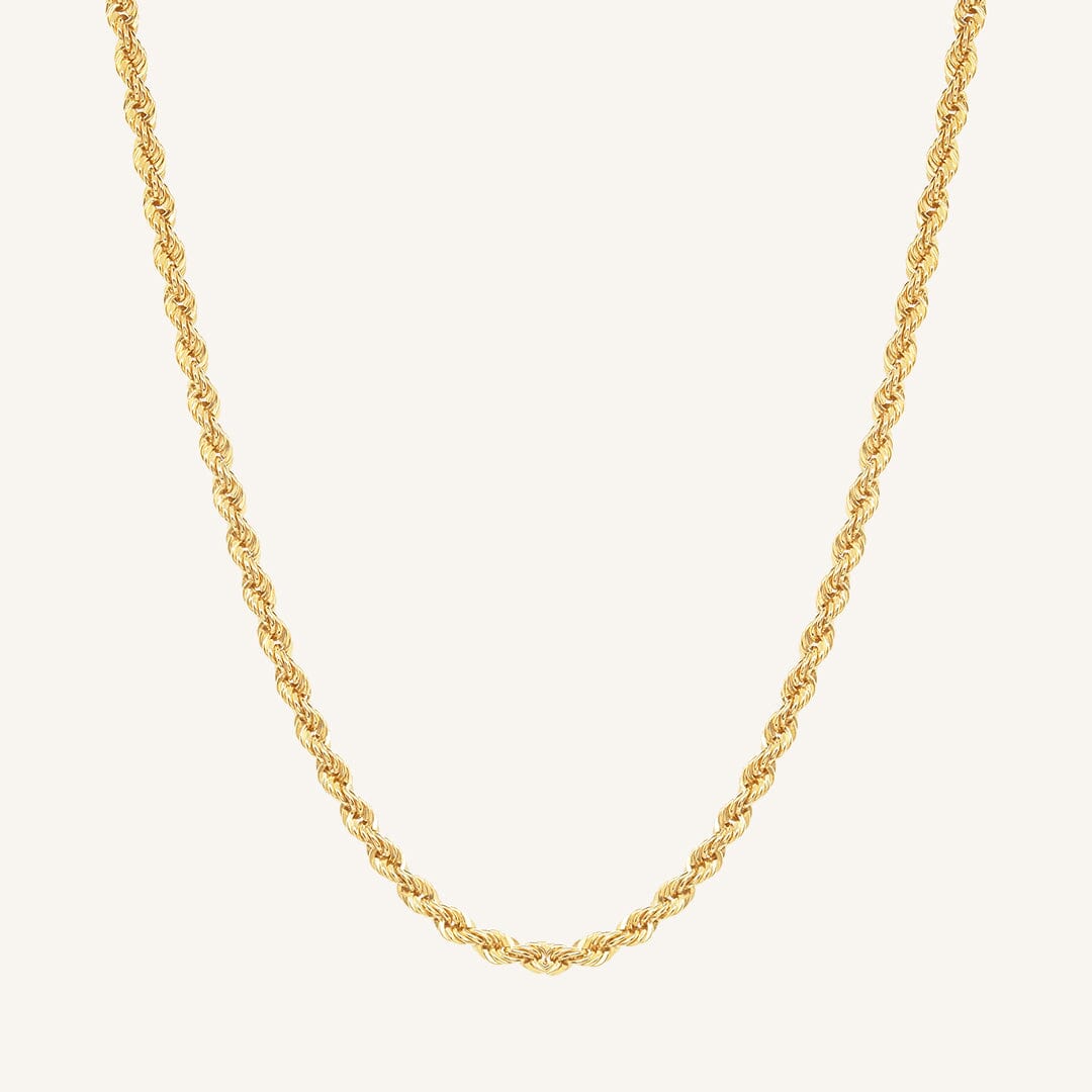 A gold rope chain necklace on a plain background.