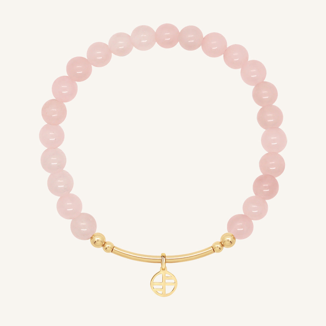 Pink beaded bracelet with a gold charm on a white background