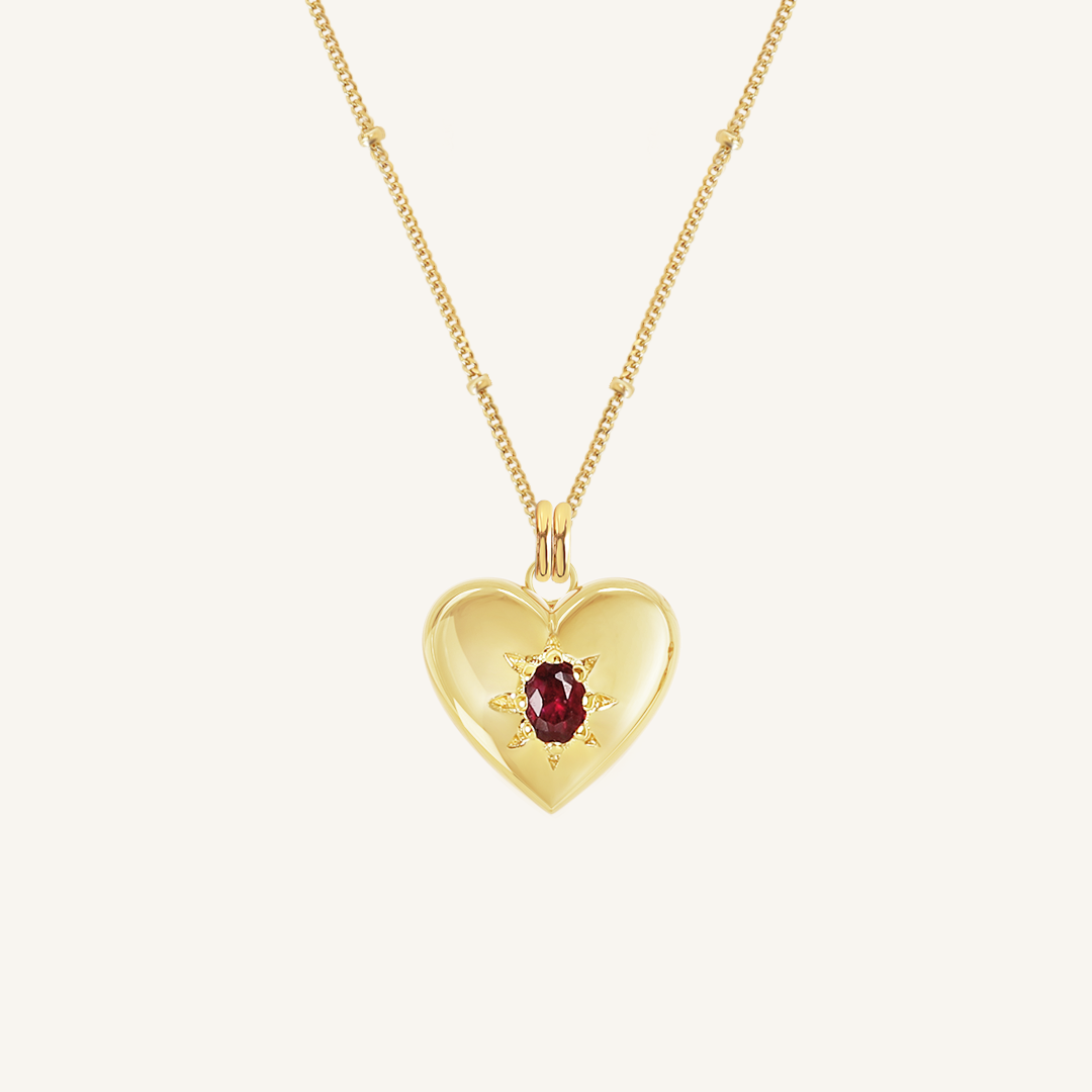 gold heart shaped charm with deep red oval cubic zirconia on bobble chain on white background