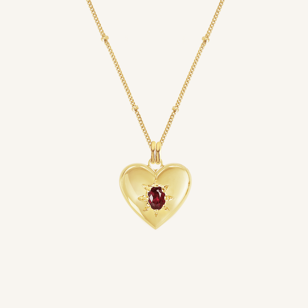 gold heart shaped charm with deep red oval cubic zirconia on bobble chain on white background