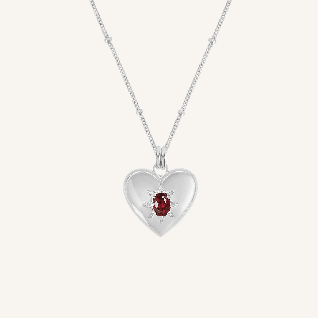 silver heart shaped charm with deep red oval cubic zirconia on bobble chain on white background