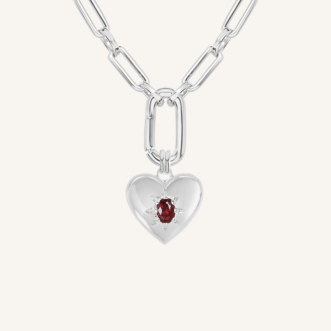 silver heart shaped charm with deep red oval cubic zirconia on link chain on white background