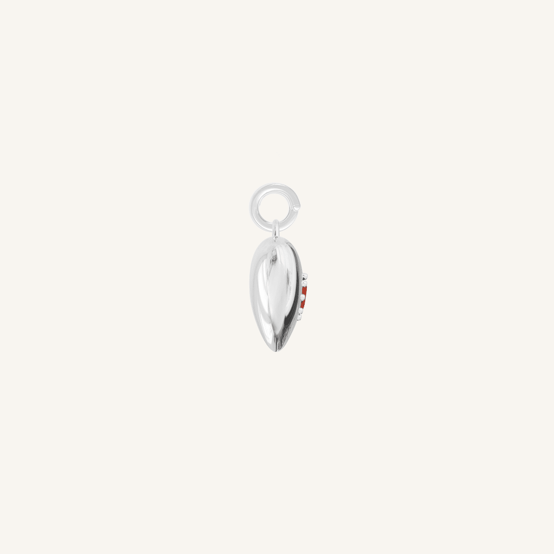 silver heart shaped charm with deep red oval cubic zirconia on white background side profile
