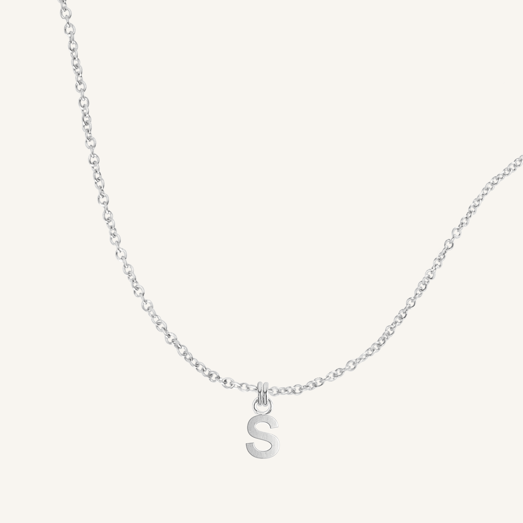 Silver necklace with a 'S' pendant on a light gray background