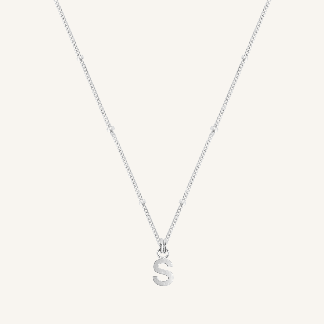 Silver necklace with a 'S' pendant on a light gray background
