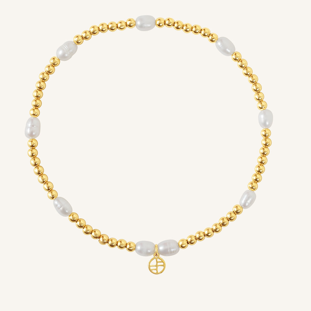 A coloured stretchy anklet with freshwater pearls and a small gold charm, displayed against a white background.
